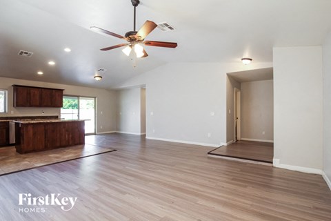 A spacious room with a ceiling fan and wooden flooring.