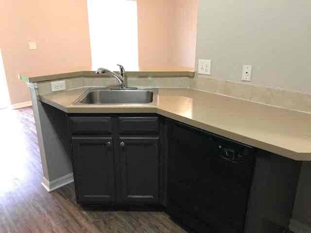A kitchen with black cabinets and a stainless steel sink.