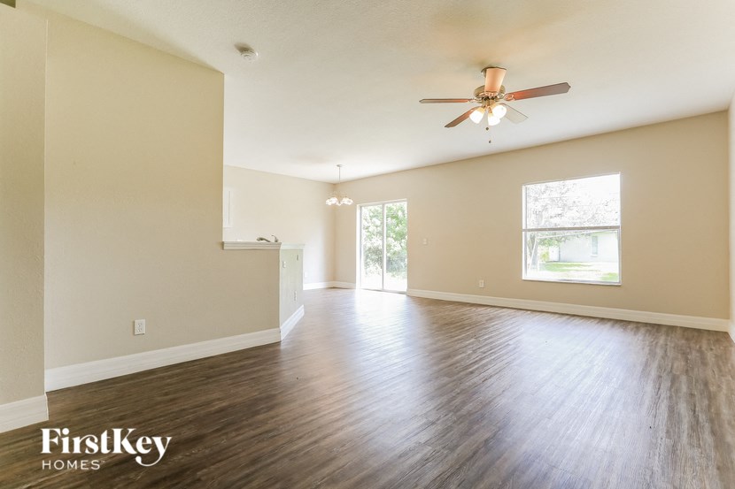 A spacious room with wooden floors and a ceiling fan.