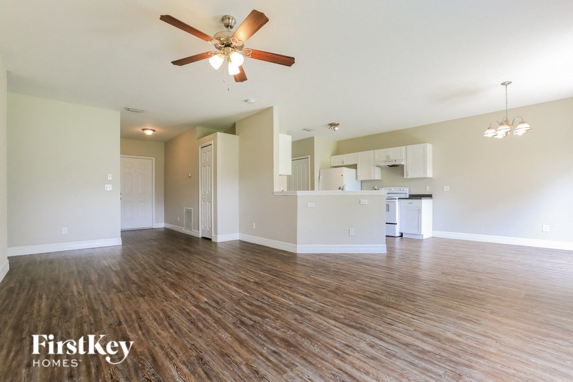 A spacious living room with a ceiling fan and wooden flooring.