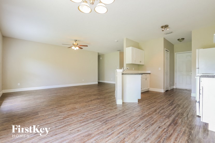 A spacious room with wooden flooring and a ceiling fan.