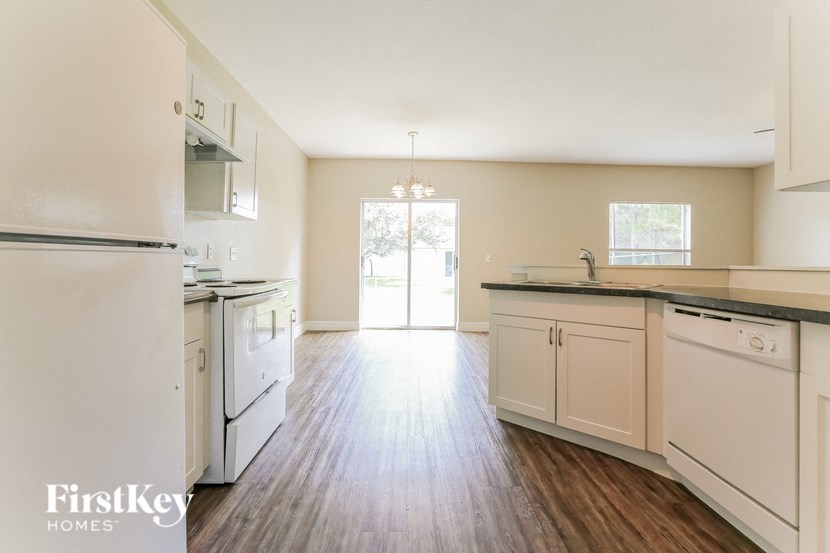 A kitchen with white appliances and wooden floors.