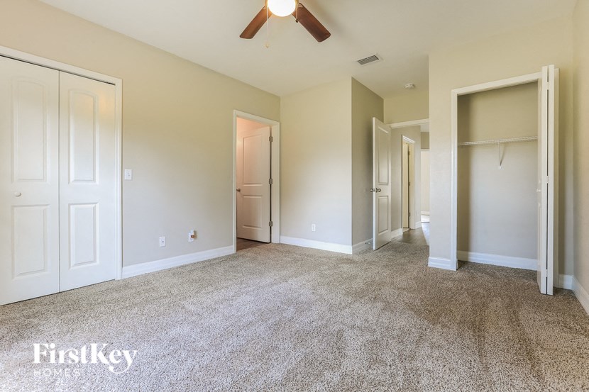 A spacious room with a carpeted floor and a ceiling fan.
