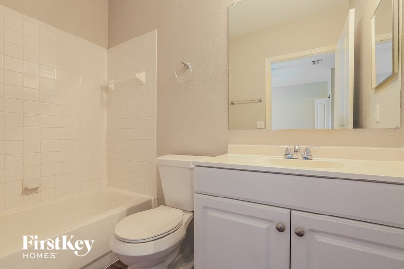 A white bathroom with a toilet, sink, and mirror.