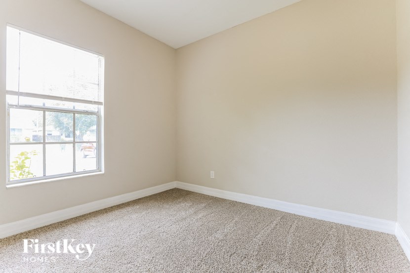 A room with a carpeted floor and a window letting in light.