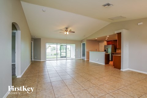 A spacious living room with a kitchen in the background.