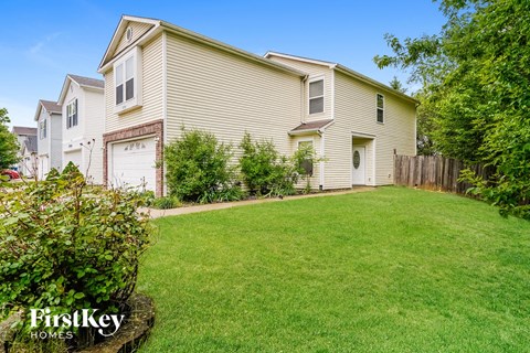 A house with a lawn and a bush in front of it.