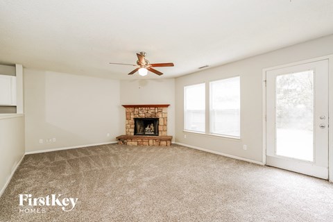A spacious living room with a fireplace and a ceiling fan.
