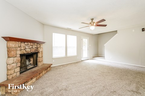 A spacious room with a fireplace and a carpeted floor.