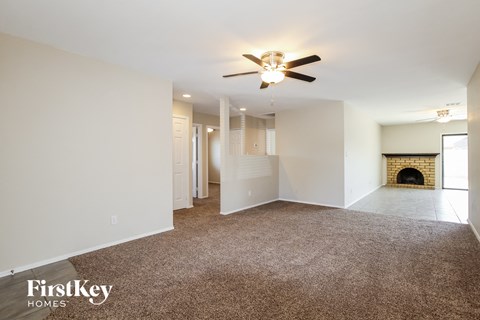 A spacious living room with a fireplace and a ceiling fan.