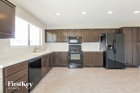 A kitchen with brown cabinets and black appliances.
