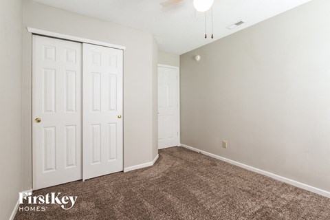 a bedroom with a carpeted floor and two closet doors