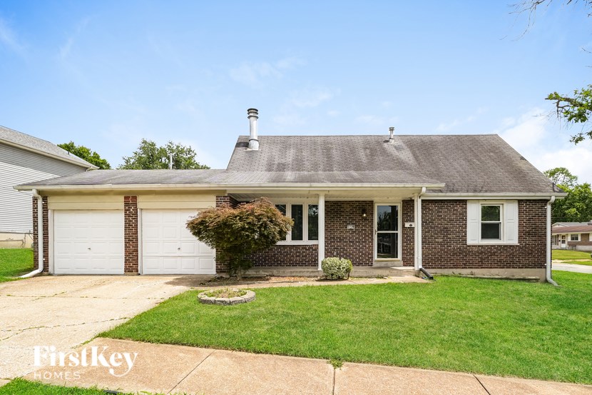 A brick house with a white garage door and a chimney on the roof.