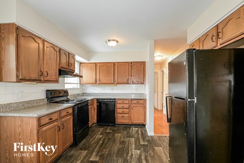 A kitchen with wooden cabinets and a black refrigerator.