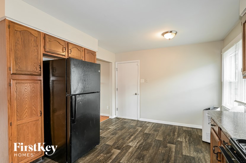 A kitchen with a black fridge and wooden cabinets.