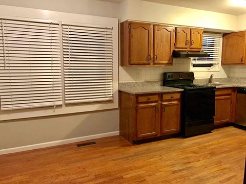 a kitchen with wooden cabinets and a stove and a window
