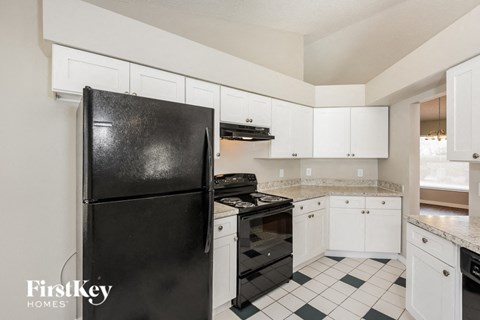 a kitchen with white cabinets and black appliances and a black refrigerator