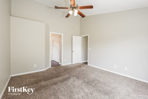 the spacious living room with carpet and ceiling fan