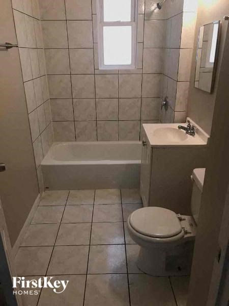 A white toilet sits in a bathroom with a white tub and sink.