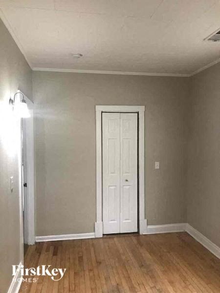 A room with a white door and wooden flooring.