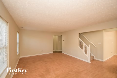 A spacious room with wooden floors and a staircase leading to another room.