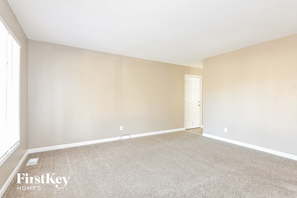 A spacious room with a carpeted floor and a door on the right side.