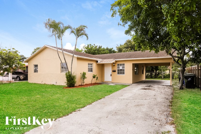 A house with a driveway and a tree in front of it.