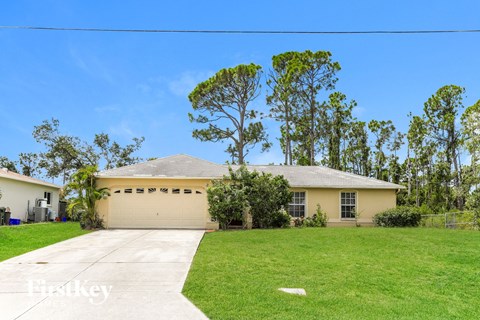 a yellow house with a lawn and a driveway