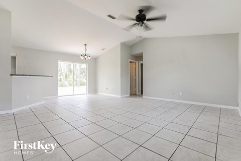 an empty living room with a ceiling fan and tiled floor