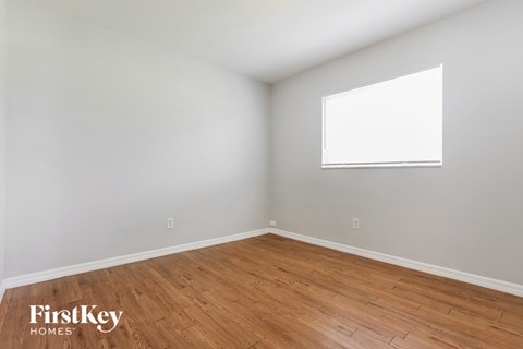 the living room with wood flooring and a window