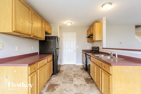 A kitchen with wooden cabinets and a black refrigerator.