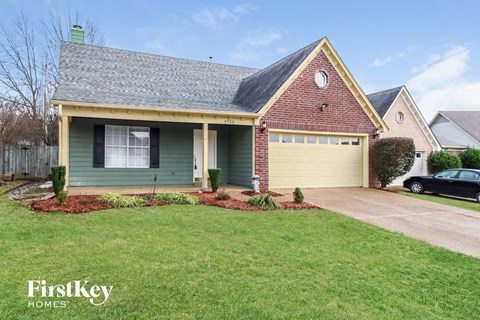 A house with a garage and a car parked in front.