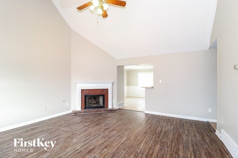 A spacious room with a fireplace and wood flooring.
