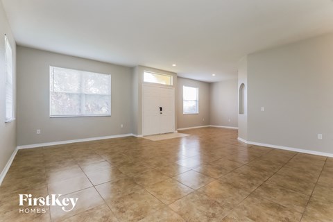 A spacious room with tile flooring and a door in the middle.
