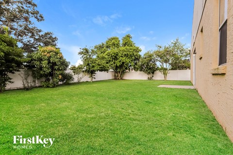 A backyard with a well-maintained lawn and trees.