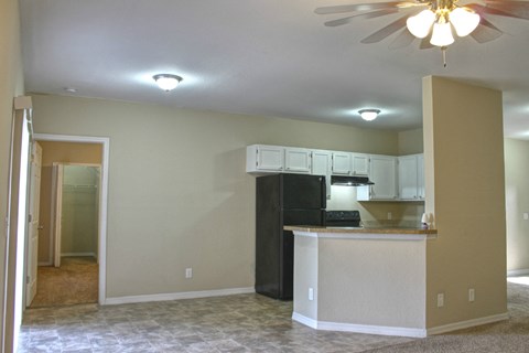 A kitchen area with a black refrigerator and a ceiling fan.