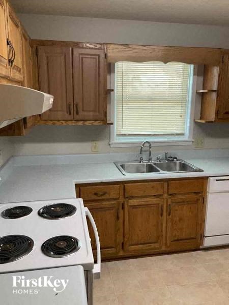 A kitchen with a stove top oven and wooden cabinets.