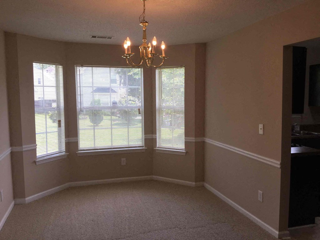 an empty dining room with windows and a chandelier