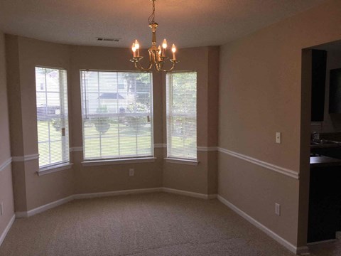 an empty dining room with windows and a chandelier