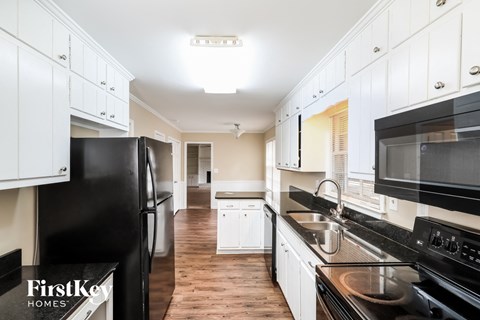 a kitchen with white cabinets and black appliances and a black refrigerator