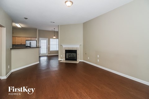 A spacious living room with a fireplace and wood flooring.
