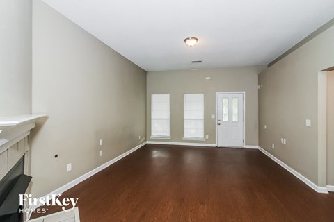 A spacious room with wood flooring and a fireplace.