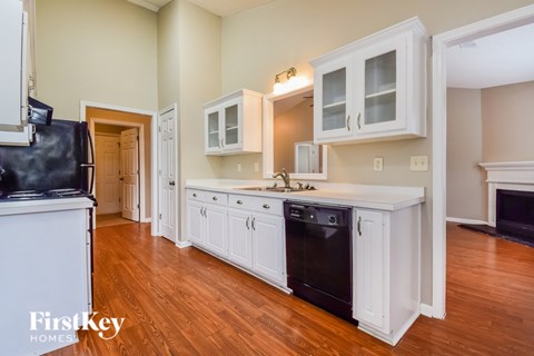 A kitchen with white cabinets and a black fridge.