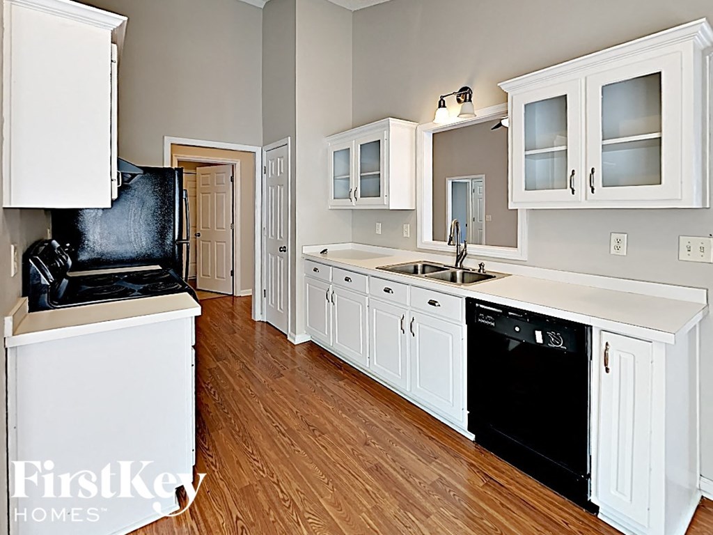 A kitchen with white cabinets and a black fridge.