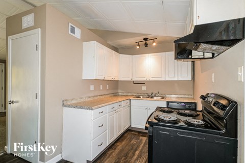 A kitchen with a black stove top oven and white cabinets.