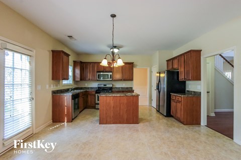 A kitchen with wooden cabinets and a chandelier hanging from the ceiling.