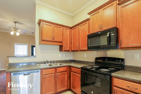 A kitchen with wooden cabinets and a black microwave above the stove.