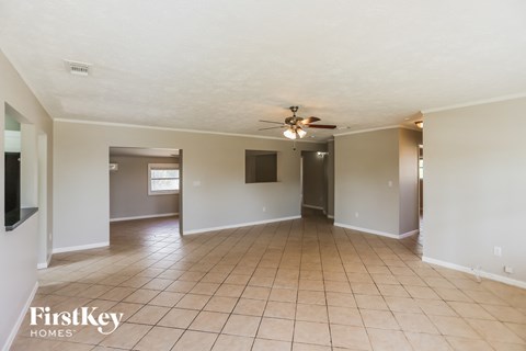 an empty living room with tile flooring and a ceiling fan