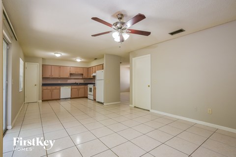 A spacious kitchen and living room with a ceiling fan.