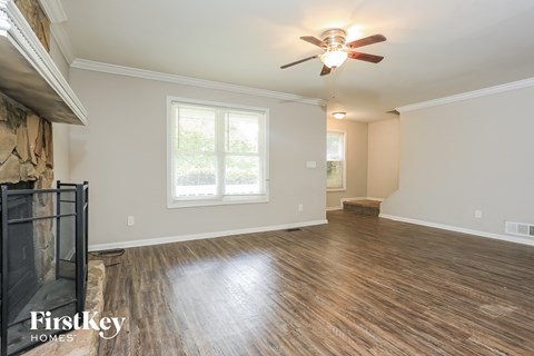 an empty living room with a ceiling fan and a fireplace